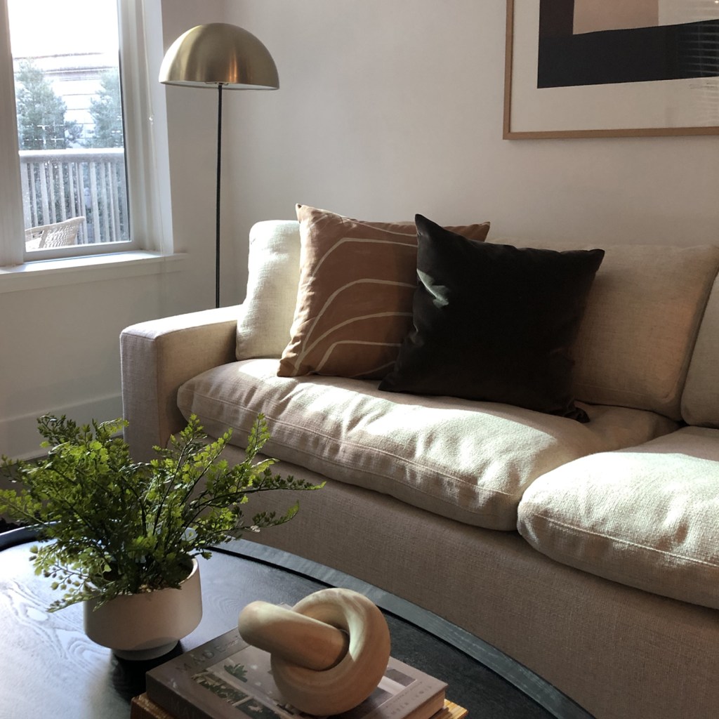 Simple refine living room with a white sofa paired with warm earthy color pillows  